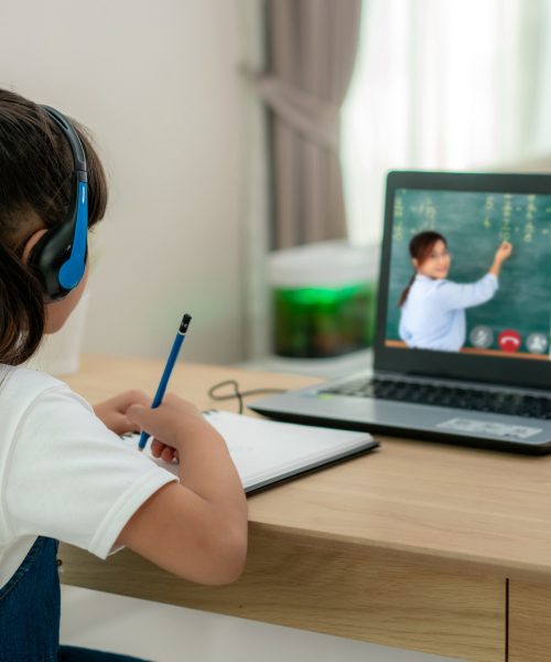 Asian girl student video conference e-learning with teacher and classmates on computer in living room at home. Homeschooling and distance learning ,online ,education and internet.